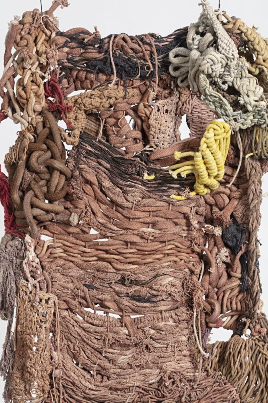 A hanging textile sculpture made of woven fibers and knots.