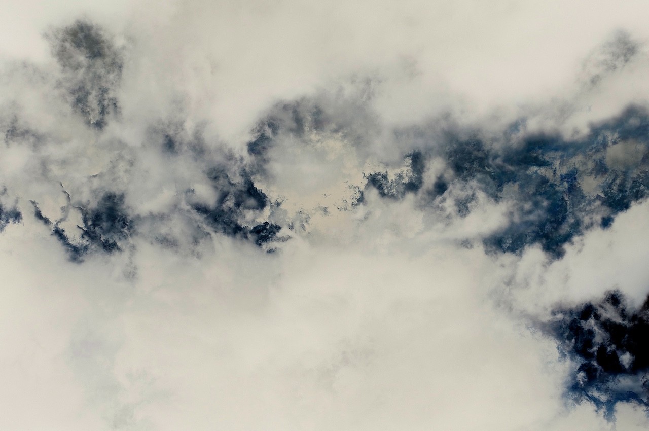 A moody sky filled with billowing clouds in shades of white and deep blue.