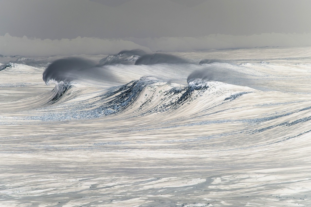 A large wave in the middle of a snow covered field.