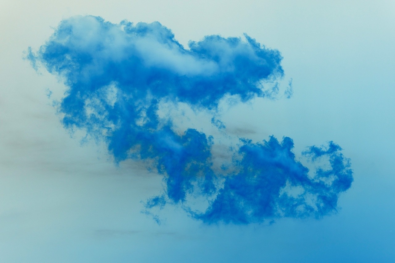 A vibrant blue ink cloud diffusing in a misty, pale background.