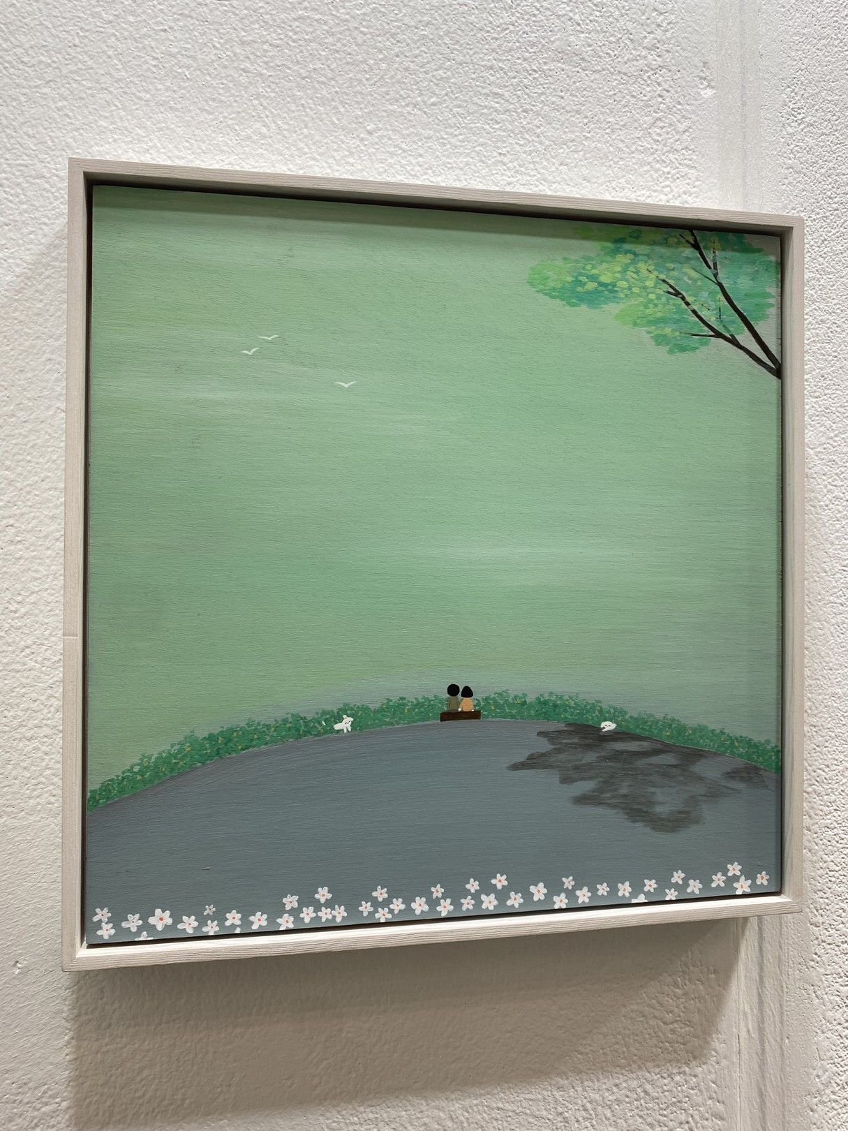 A serene landscape painting featuring a couple sitting on a bench overlooking a vast green expanse.