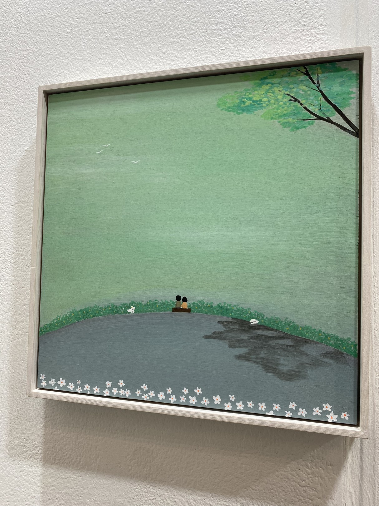 A serene landscape painting featuring a couple sitting on a bench overlooking a vast green expanse.