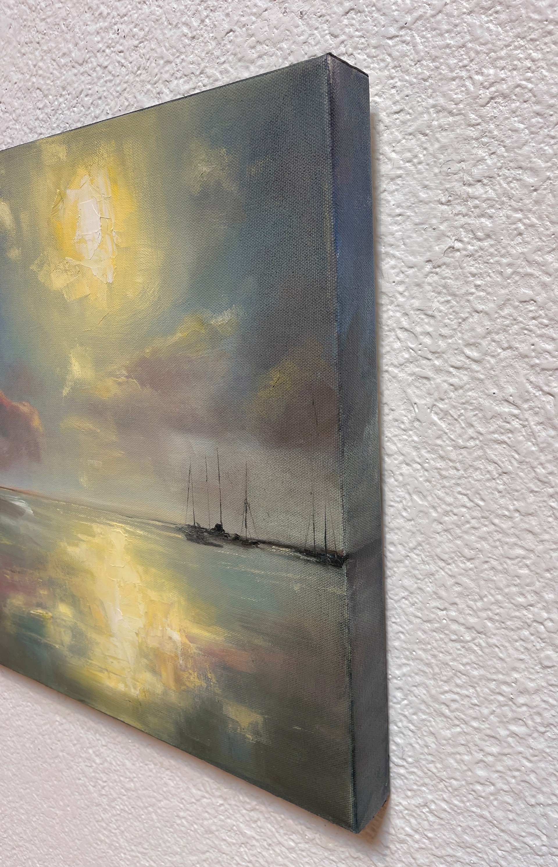 A seascape painting of a calm bay at sunset with anchored sailboats.