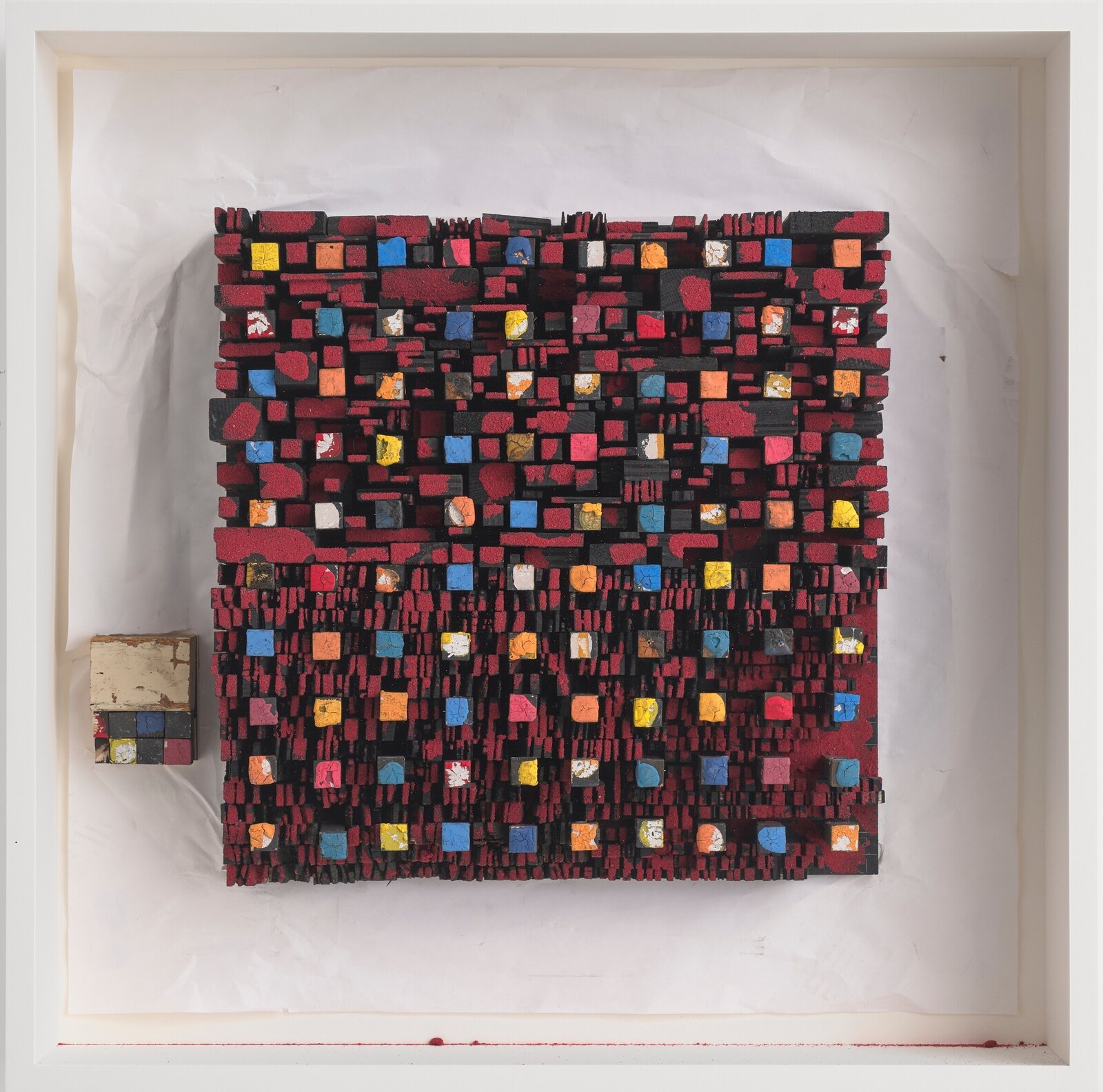A textured relief sculpture composed of small, multi-colored cubes arranged in a dense grid.