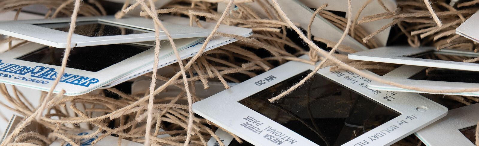 A chaotic pile of vintage slide frames tangled with twine.