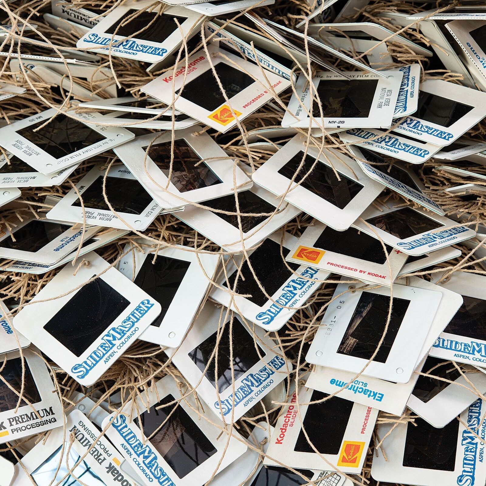 A chaotic pile of vintage slide frames tangled with twine.