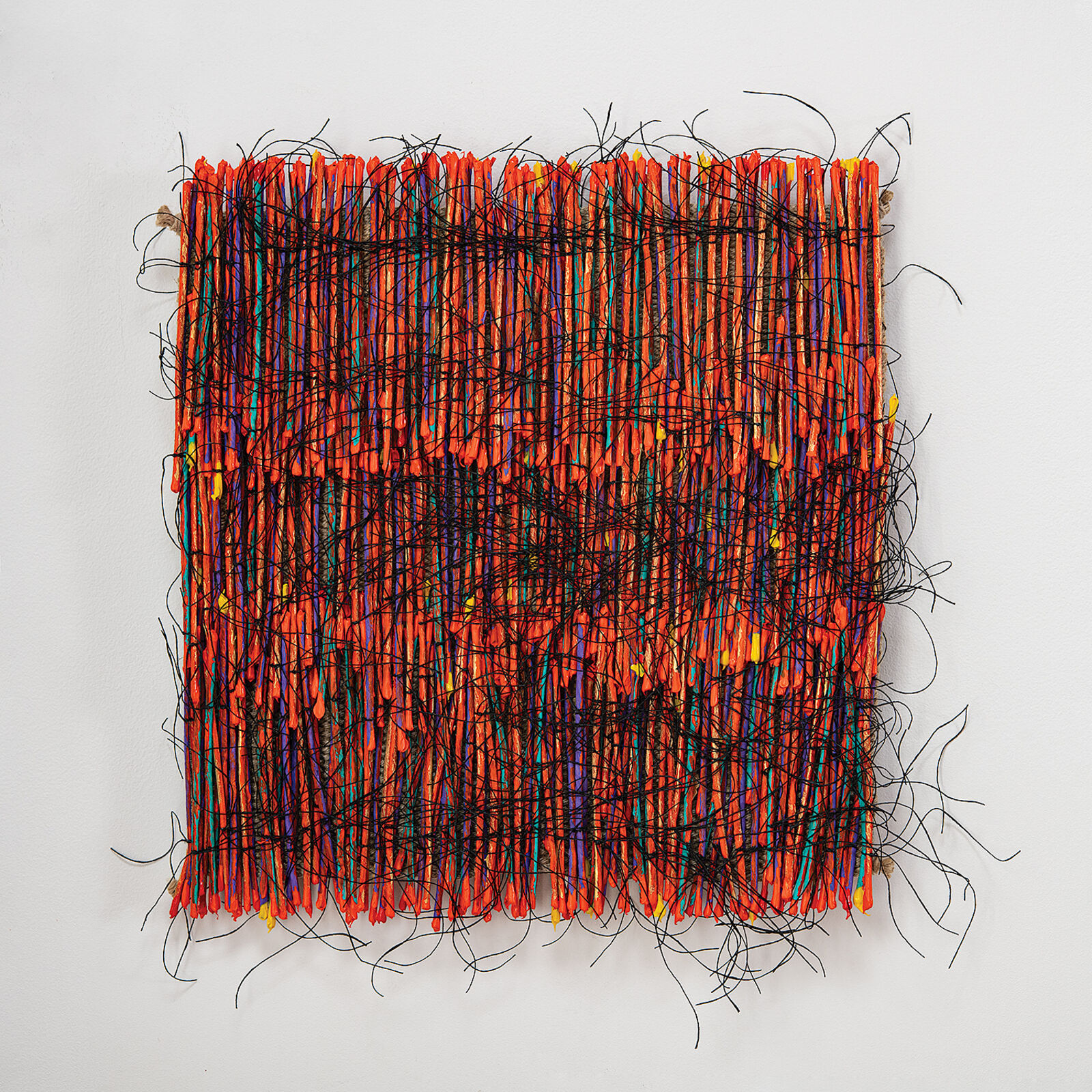 A vibrant textile artwork featuring a dense weave of orange threads interlaced with black and multicolored fibers.