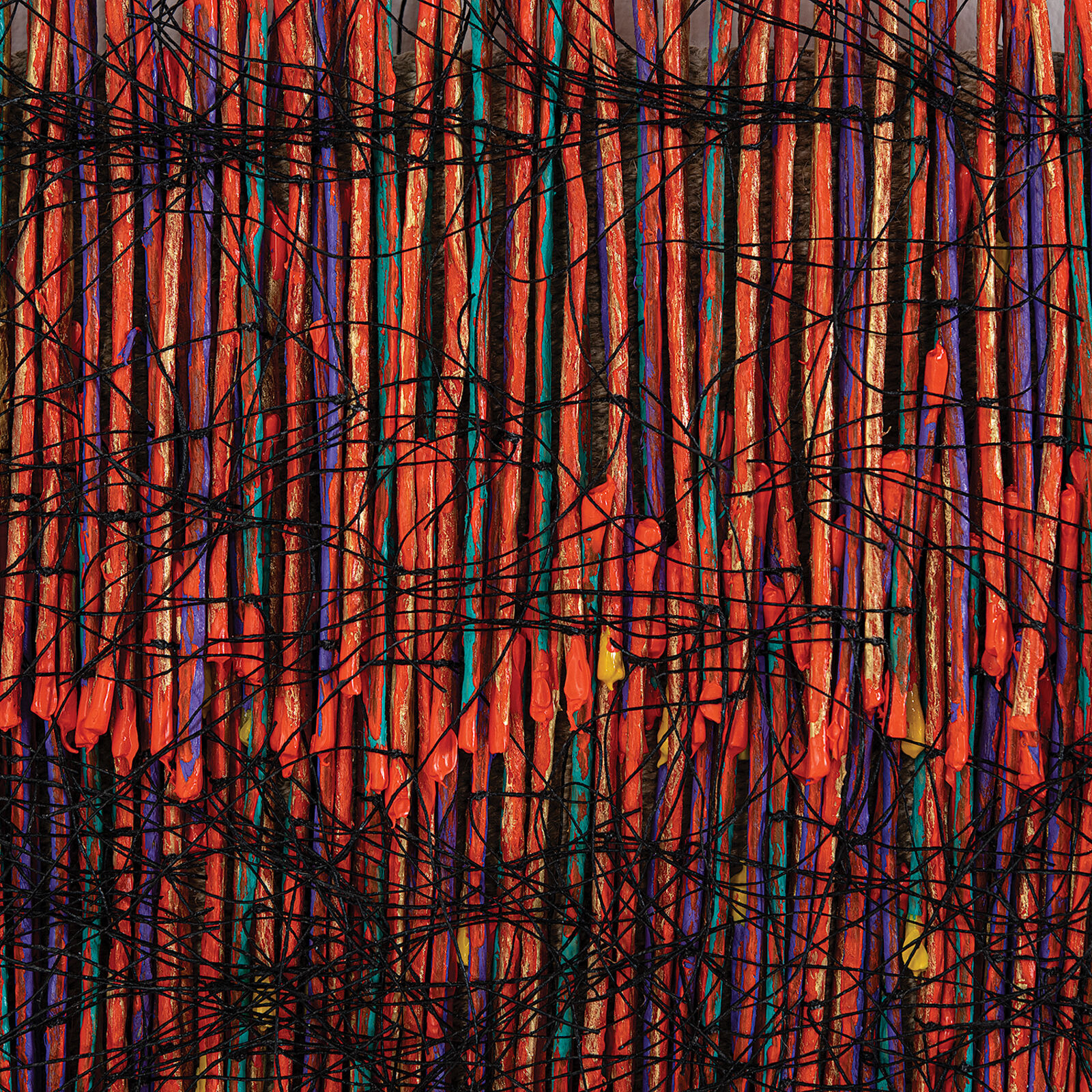 A vibrant textile artwork featuring a dense weave of orange threads interlaced with black and multicolored fibers.