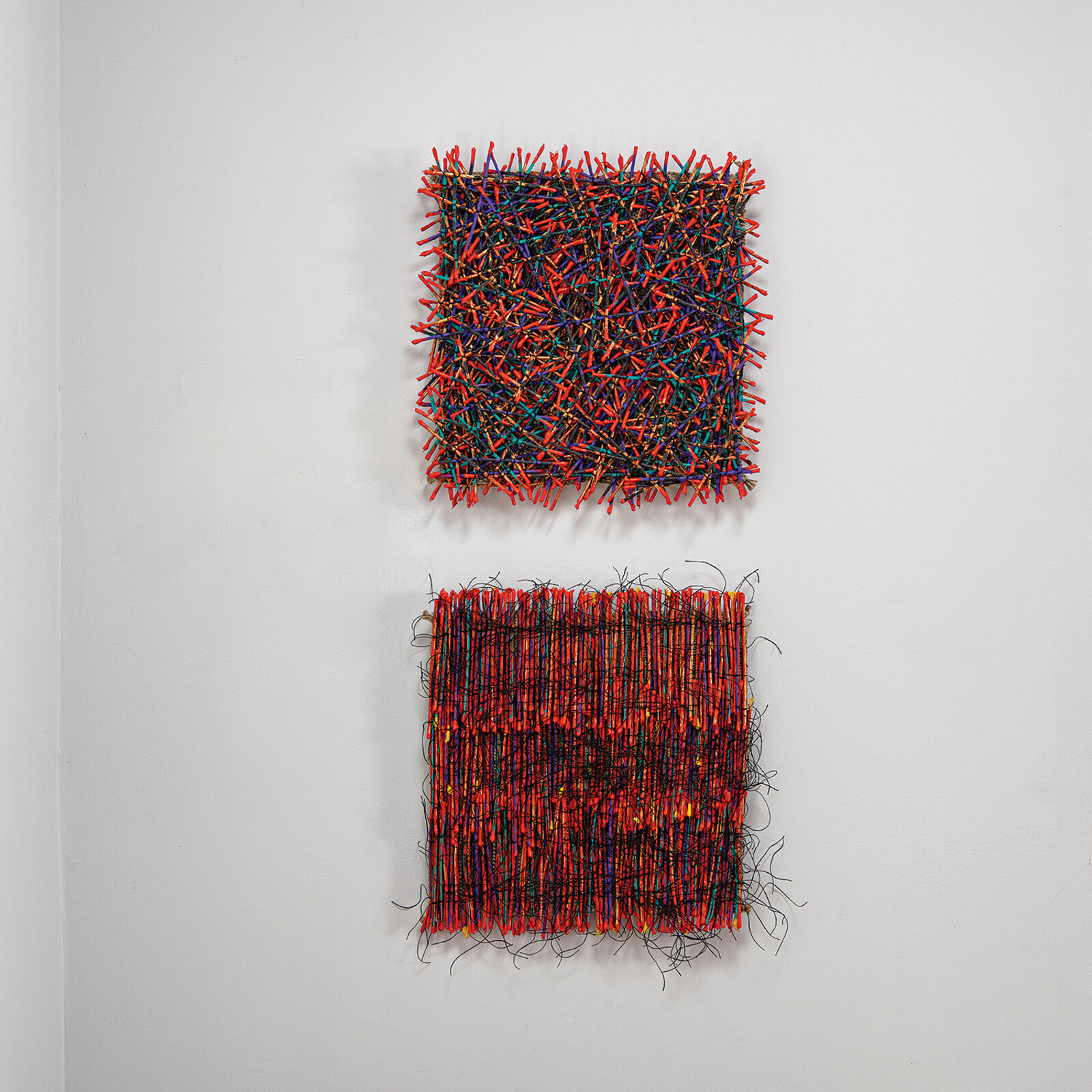 A vibrant textile artwork featuring a dense weave of orange threads interlaced with black and multicolored fibers.