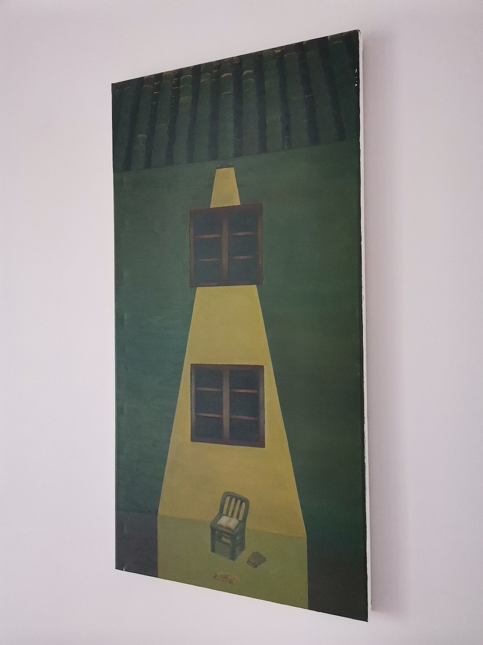 A surreal painting of a yellow house with two windows, a chair, and a book on a green background.