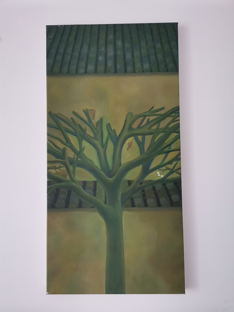 "A vertical painting of a leafless tree against a muted yellow wall with a dark tiled roof above."