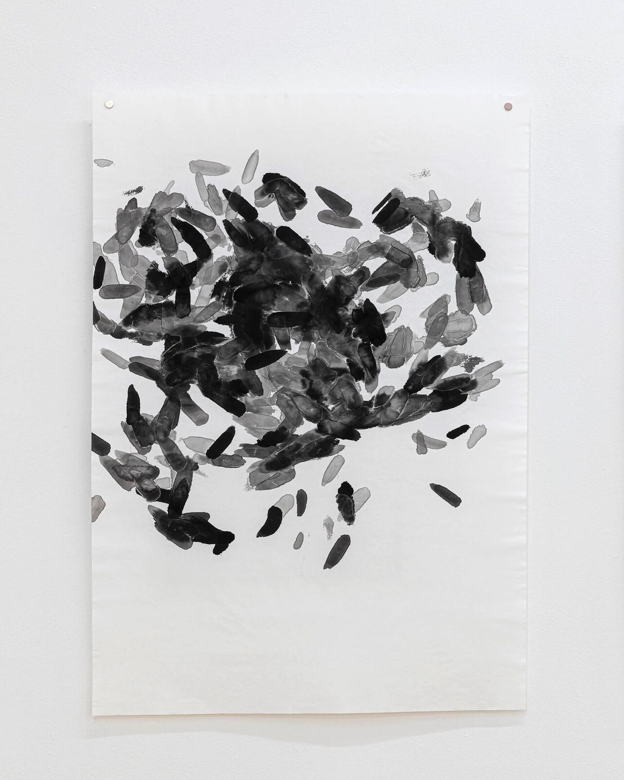 A monochromatic ink study featuring a chaotic cluster of black and grey brushstrokes on white paper.