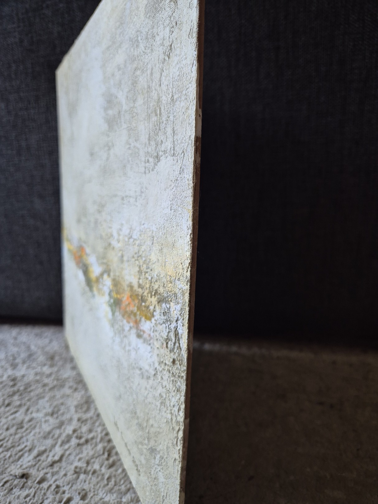 A textured abstract painting featuring a horizontal band of warm colors against a rough, neutral background.