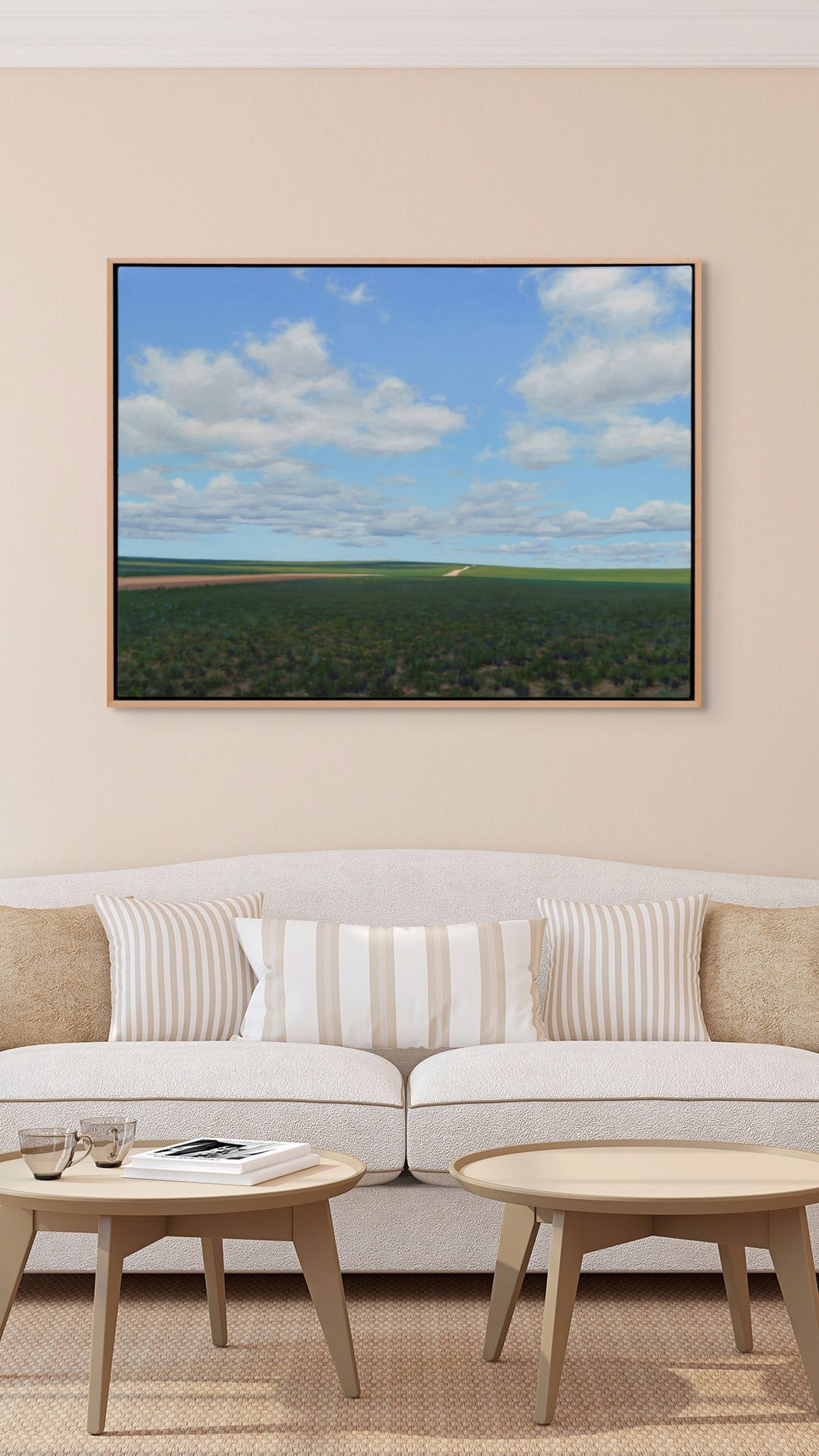 A vast landscape painting of rolling green fields under a blue sky filled with fluffy white clouds.