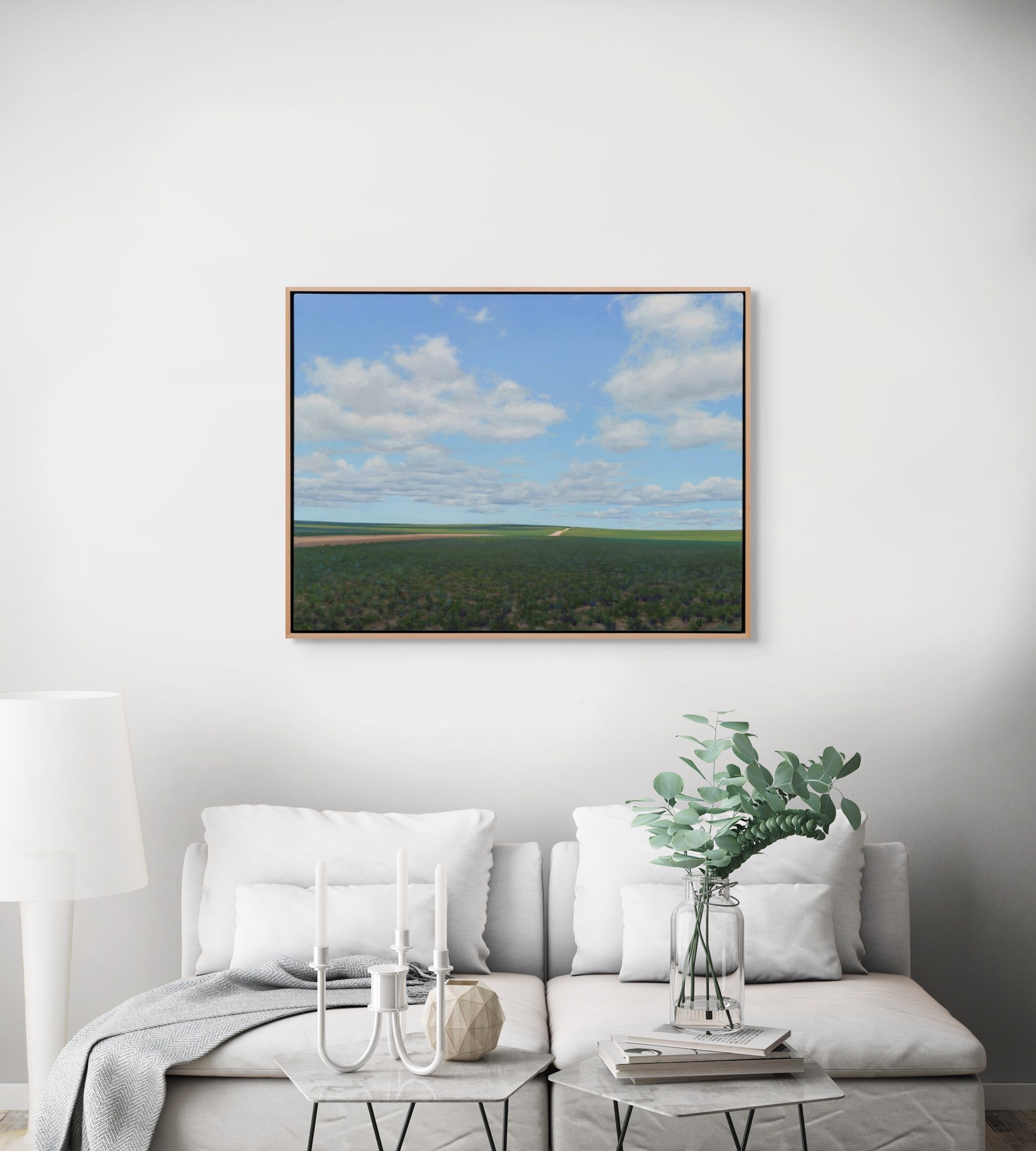 A vast landscape painting of rolling green fields under a blue sky filled with fluffy white clouds.