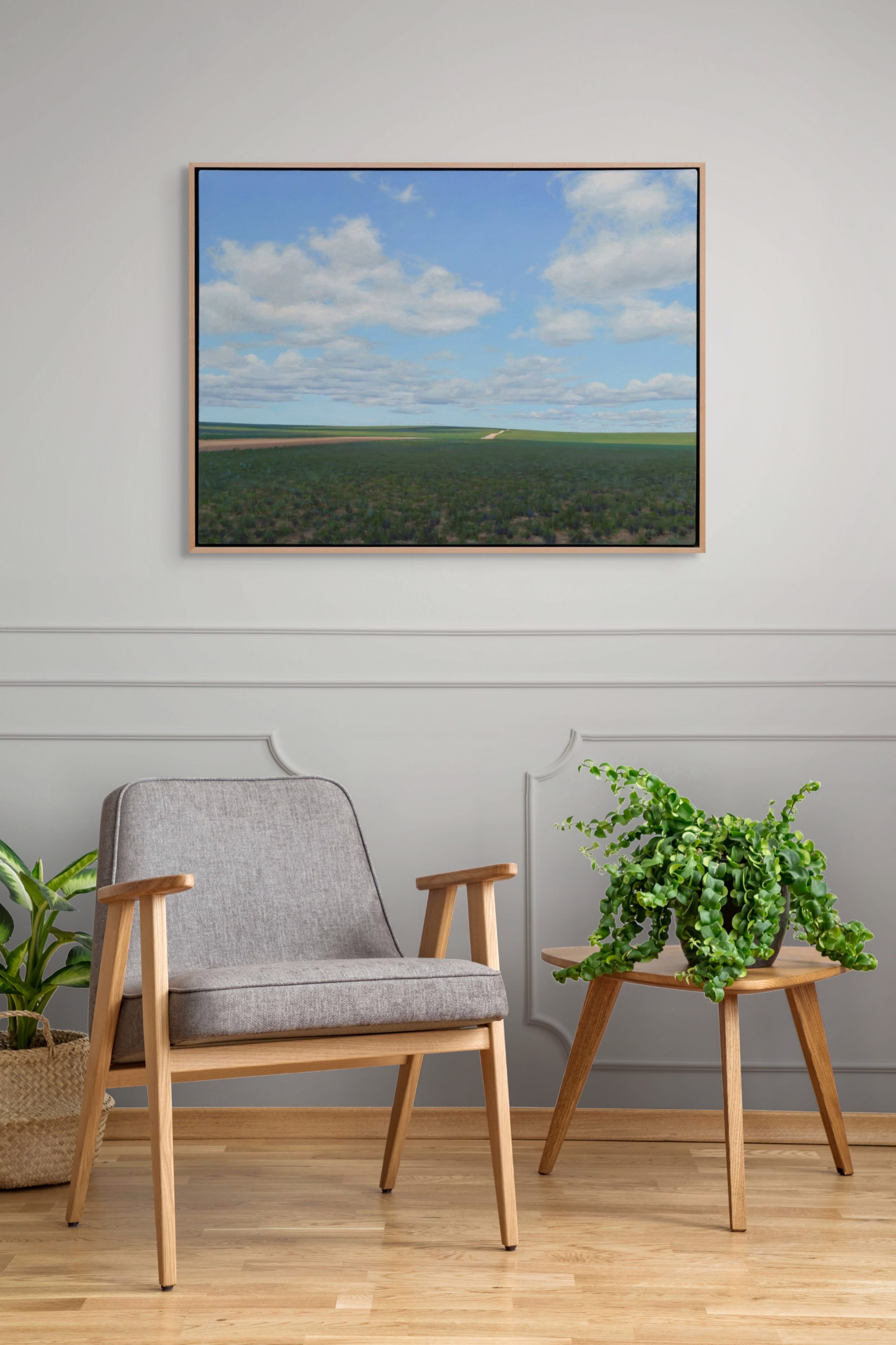 A vast landscape painting of rolling green fields under a blue sky filled with fluffy white clouds.