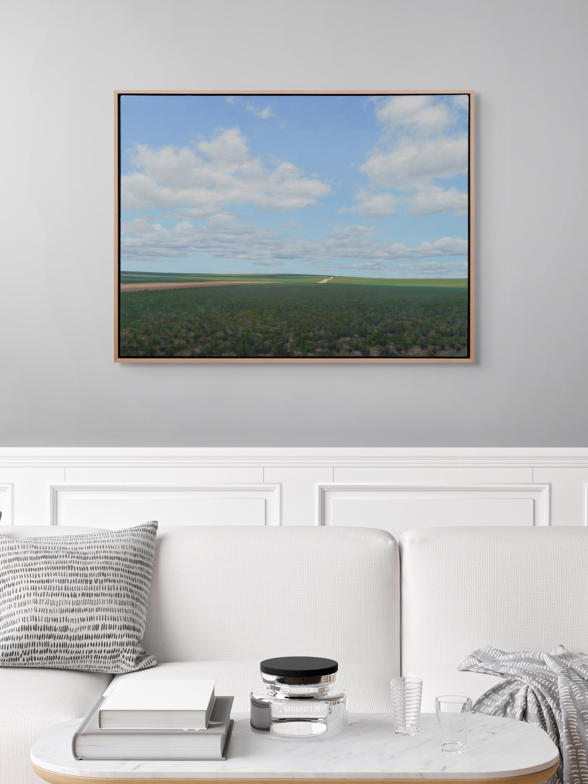 A vast landscape painting of rolling green fields under a blue sky filled with fluffy white clouds.