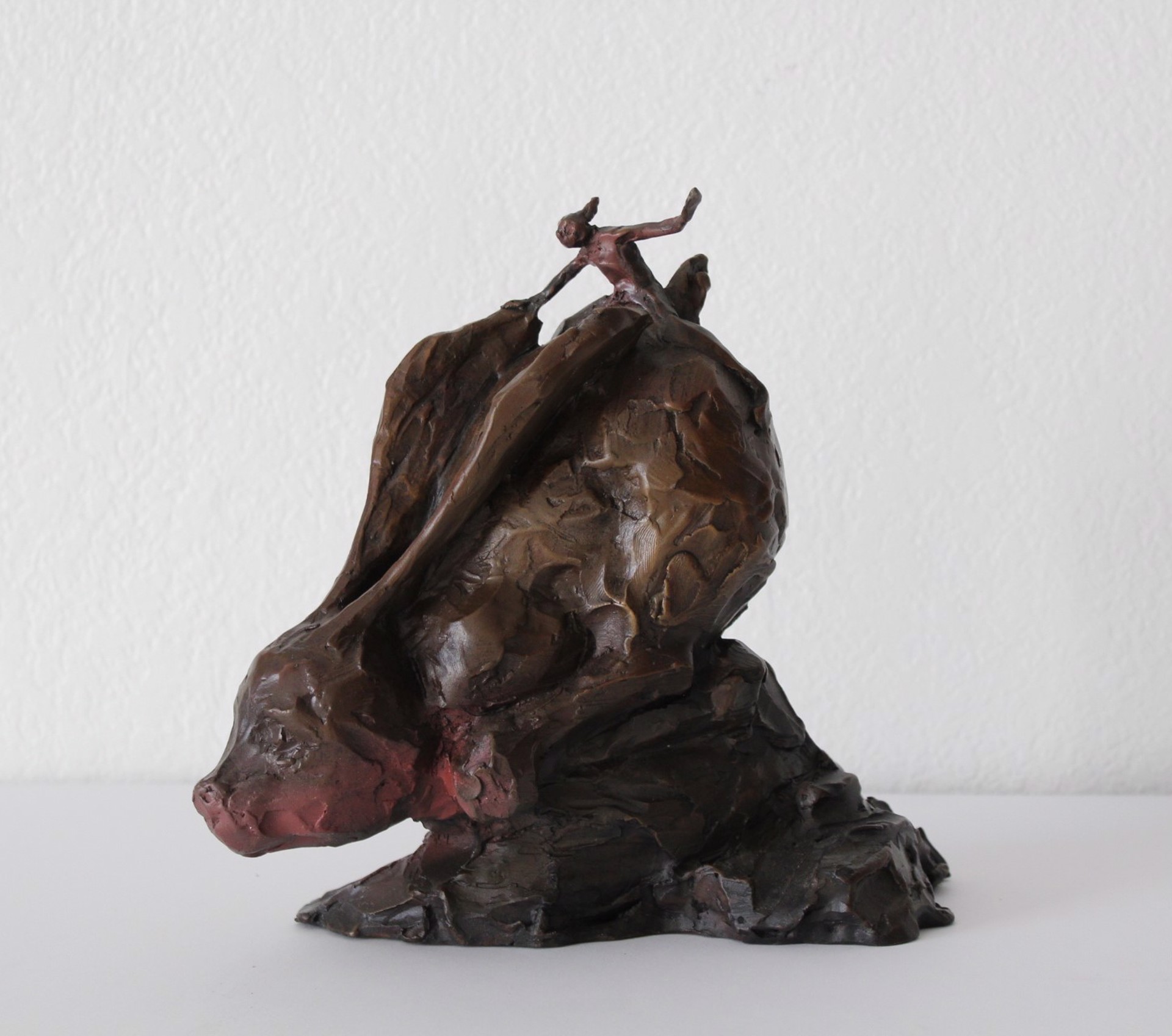 A bronze sculpture of a man riding a horse on a rock.