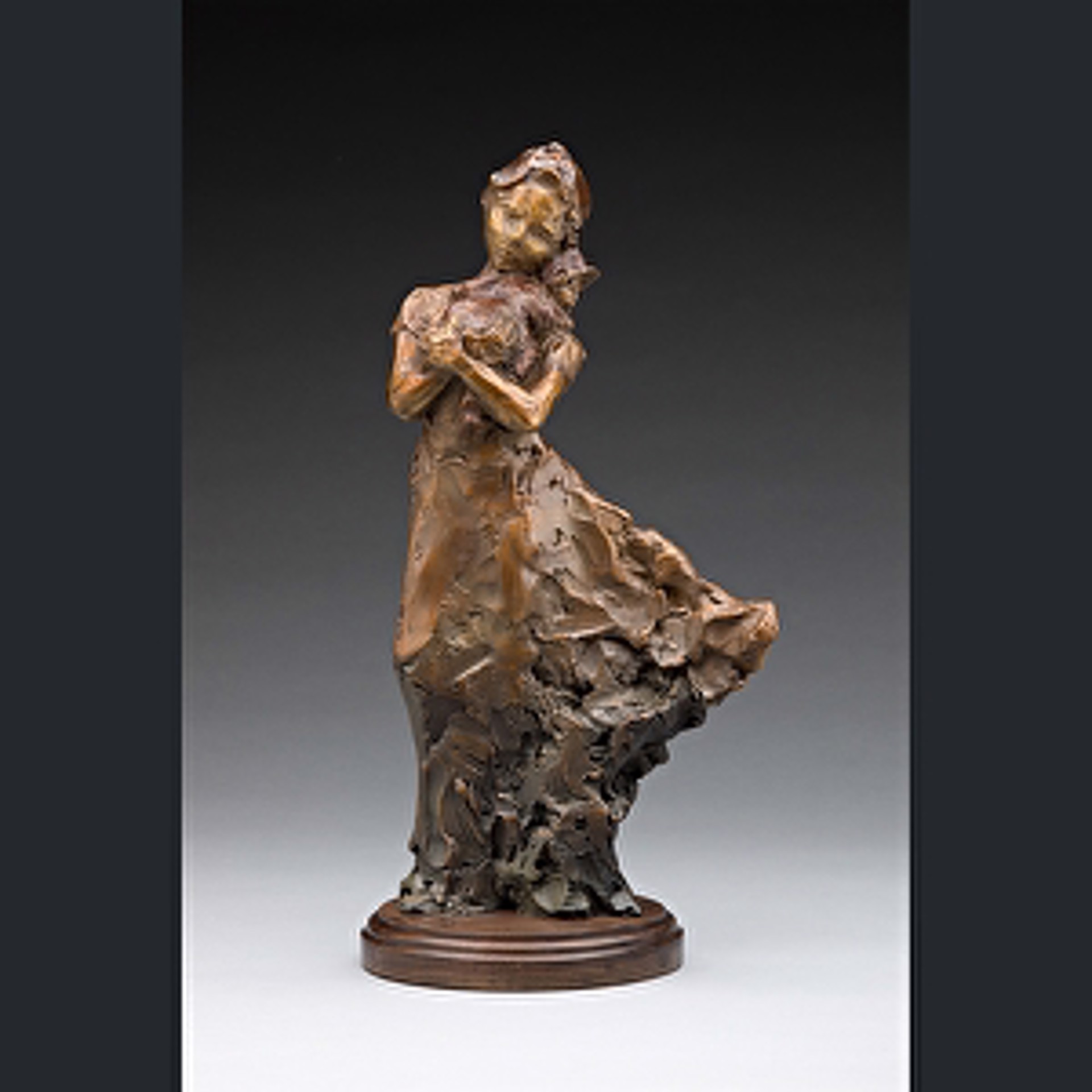 A bronze sculpture of a woman sitting on a rock.