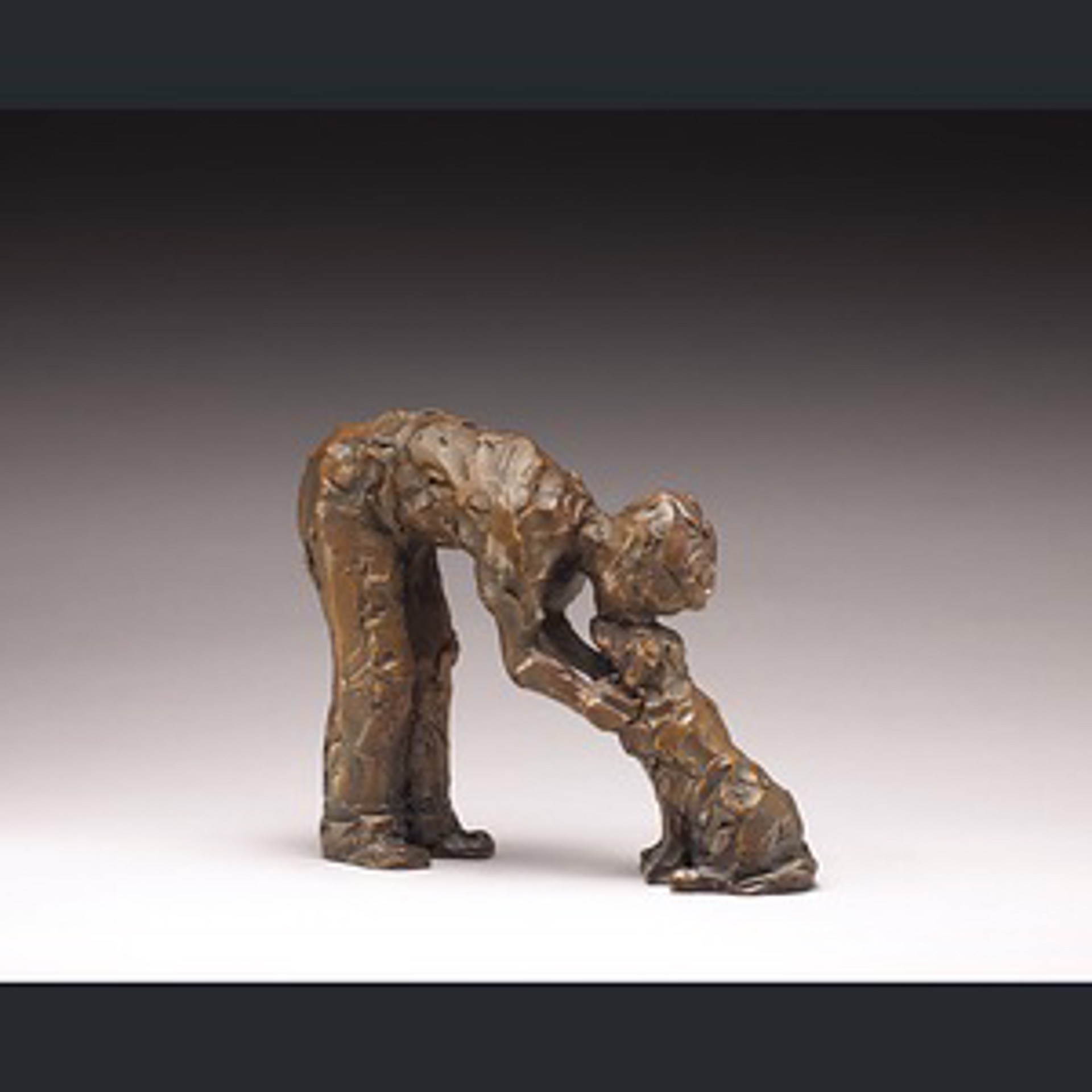 A bronze sculpture of a man bending over to pick up something.