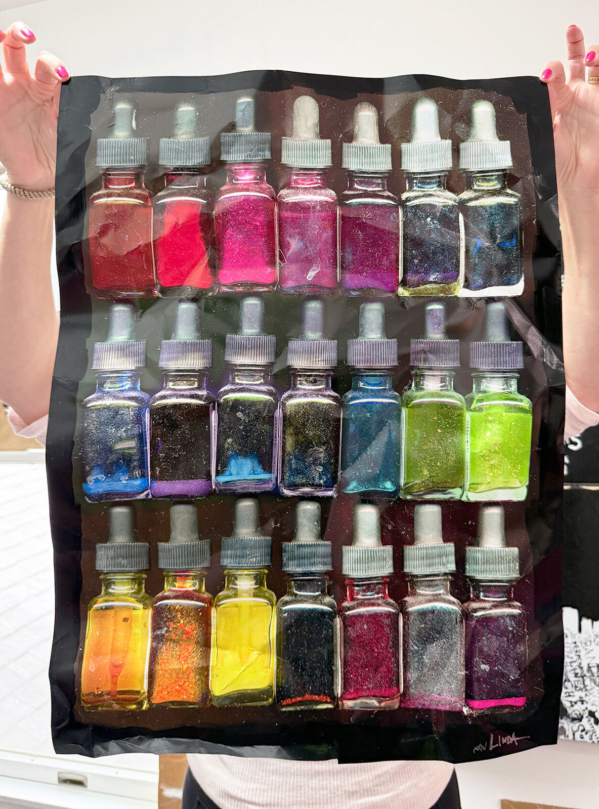 A picture of a painting with a brush and a bunch of bottles of paint.