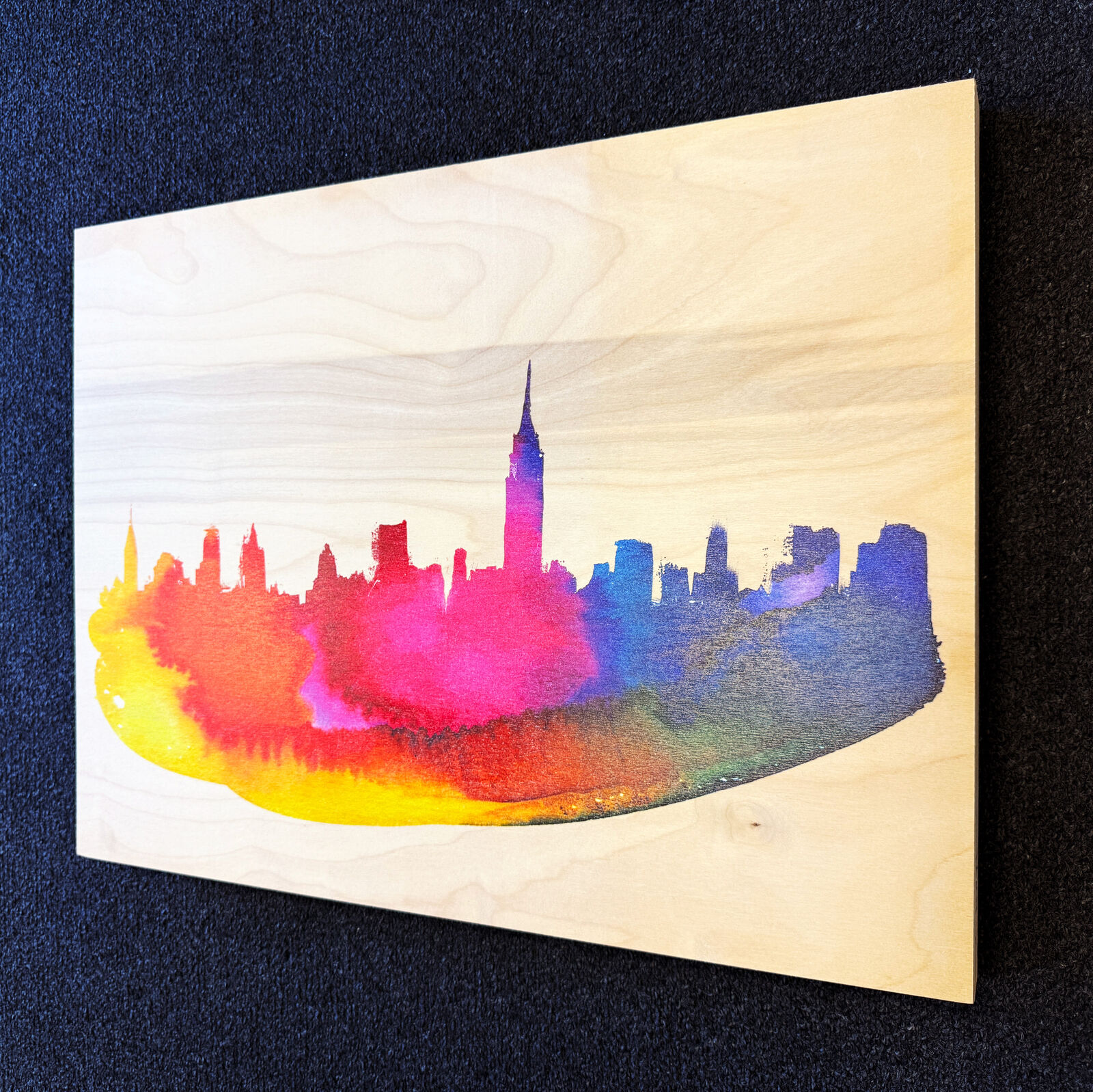 A watercolor painting of a city skyline on a wooden surface.