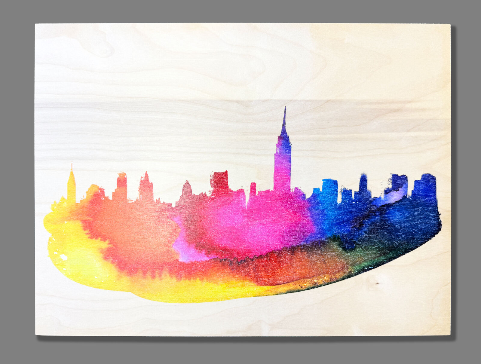 A watercolor painting of a city skyline on a wooden surface.