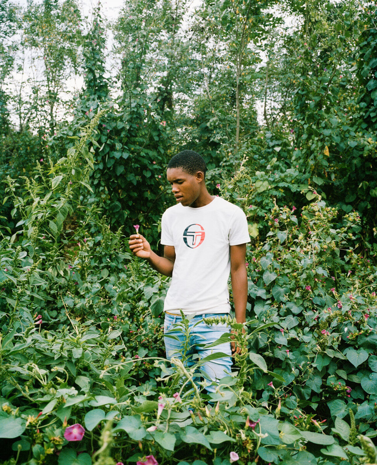A man standing in a field of flowers holding a flower.