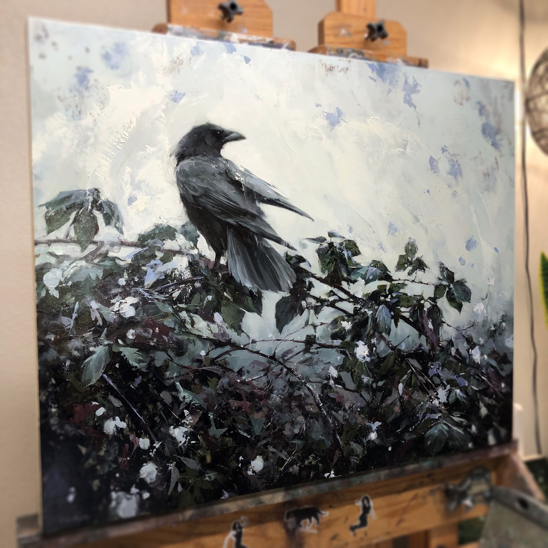 A solitary dark bird perches on a leafy branch against a textured, muted background.