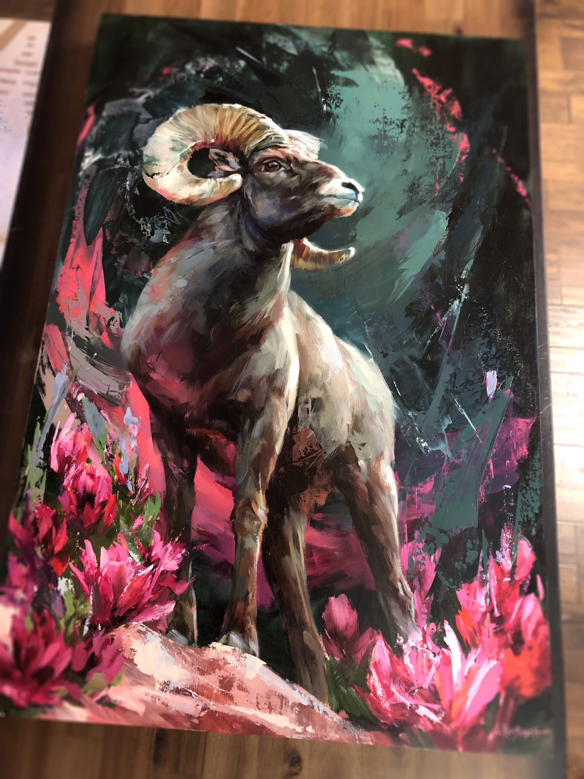 A painting of a ram standing on a rock surrounded by flowers.