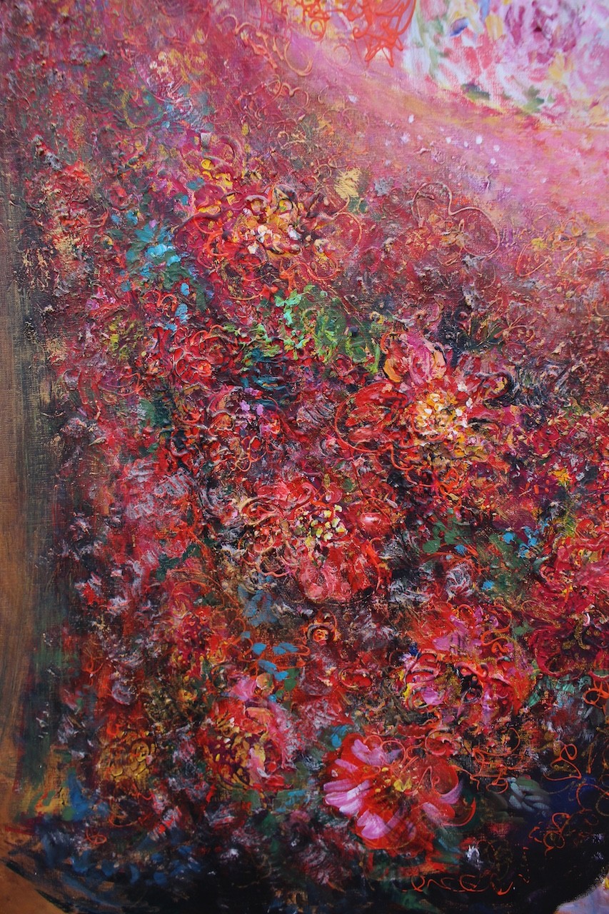 Three figures in flowing, floral-patterned gowns pose closely together against a warm background.