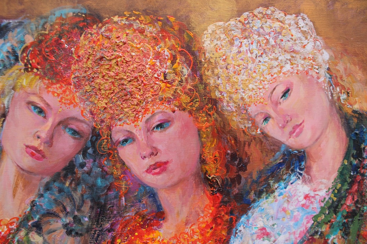 Three figures in flowing, floral-patterned gowns pose closely together against a warm background.