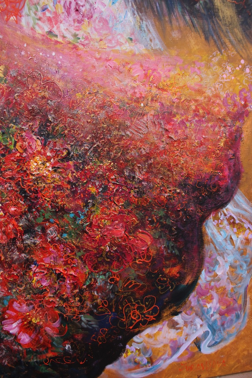 Three figures in flowing, floral-patterned gowns pose closely together against a warm background.