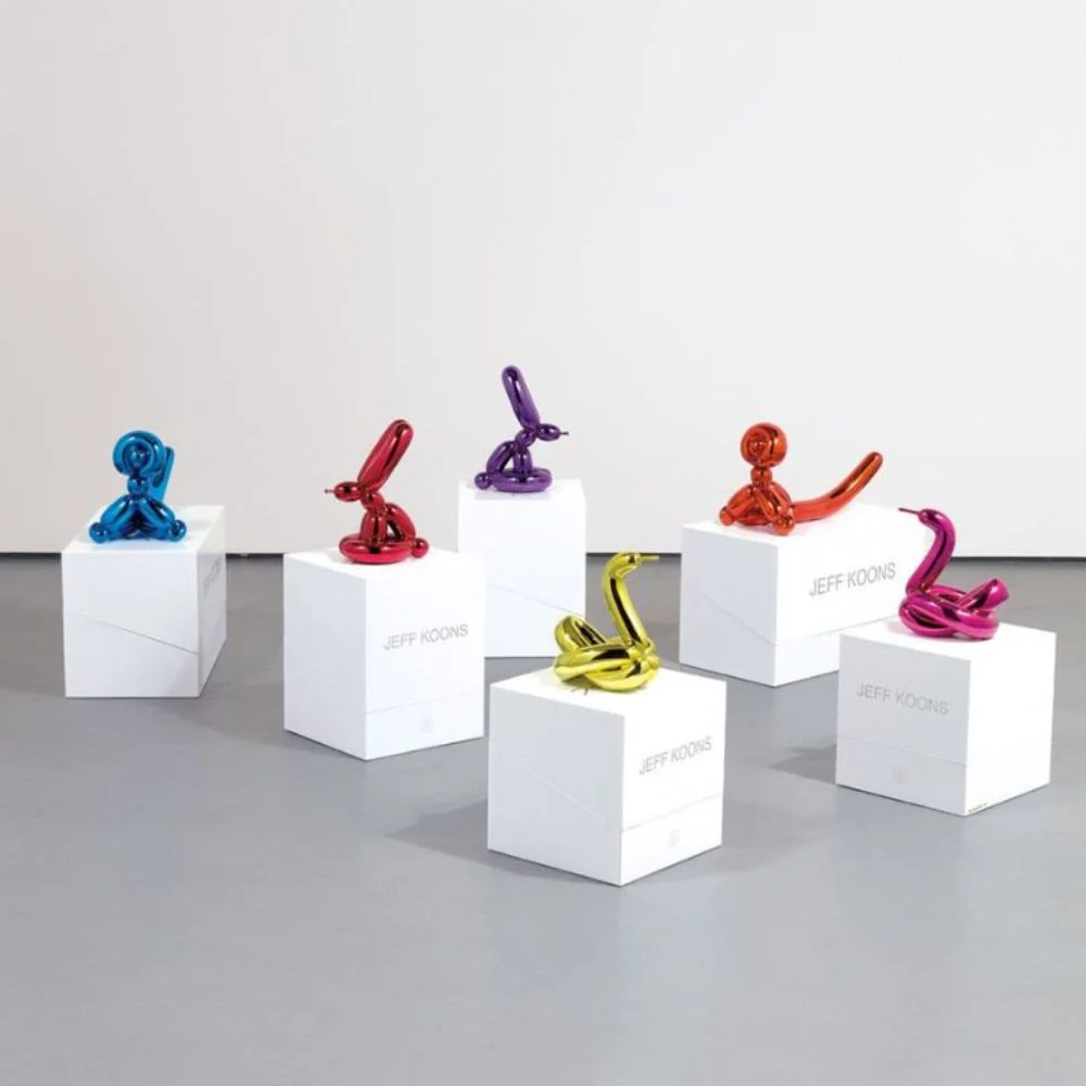 A collection of metallic balloon animal sculptures displayed on white pedestals.