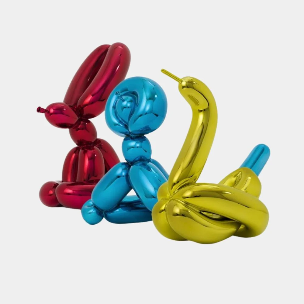 A trio of metallic balloon animal sculptures in red, blue, and gold against a plain background.