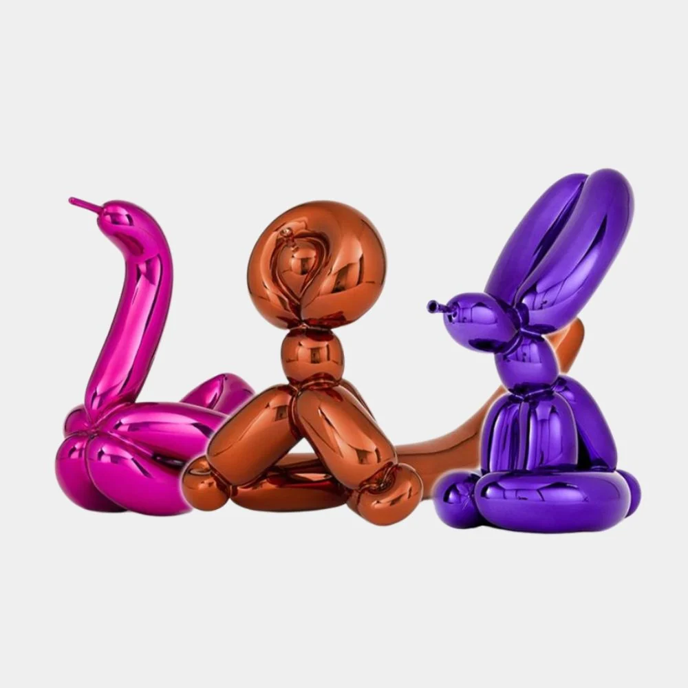 A trio of glossy, metallic balloon animal sculptures in magenta, copper, and purple against a plain background.