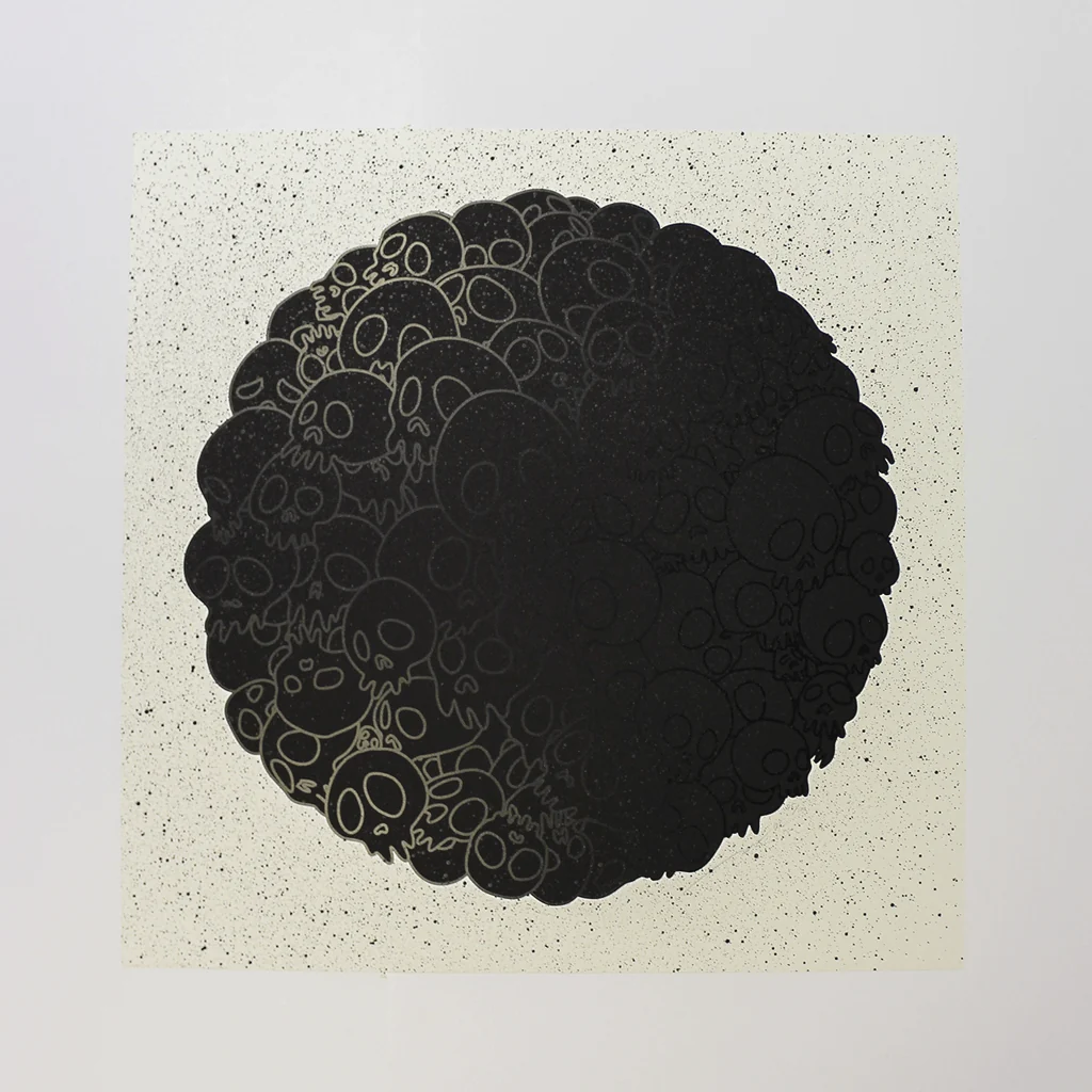 A graphic print of a dense, circular cluster of stylized skulls in black ink against a speckled off-white background.