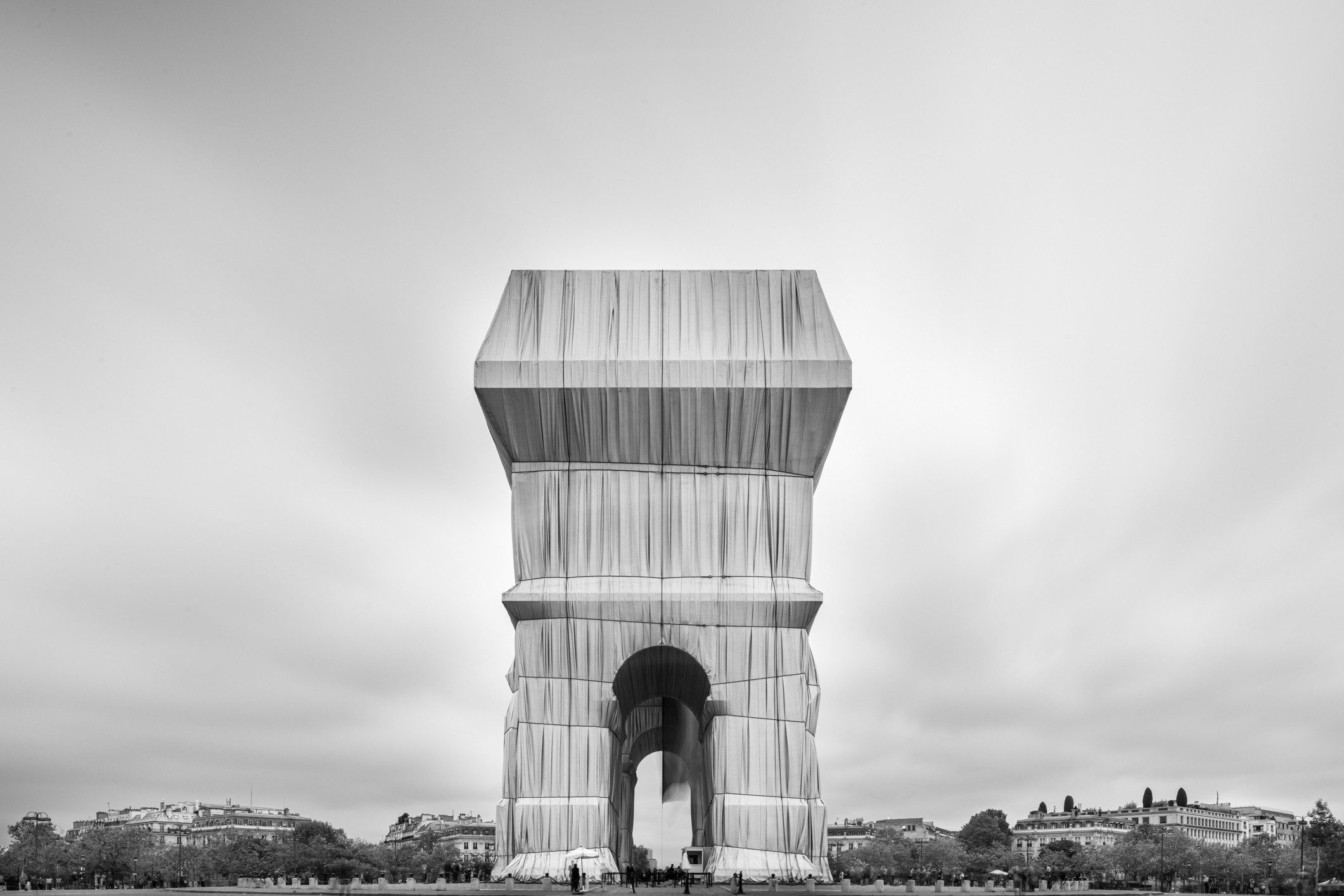 A black and white photo of a tall building in the middle of a park.