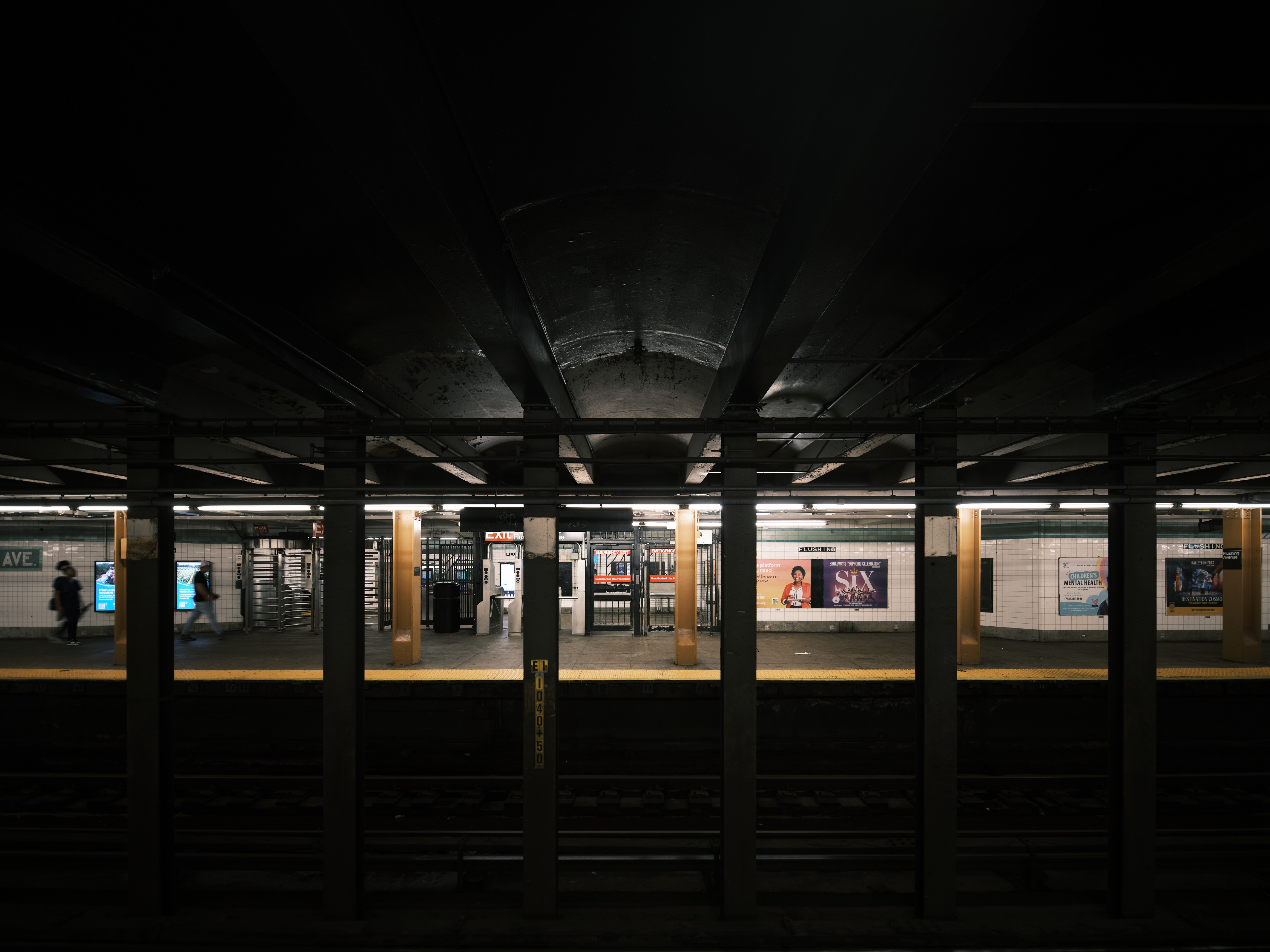 A subway station at night with people waiting for the train.