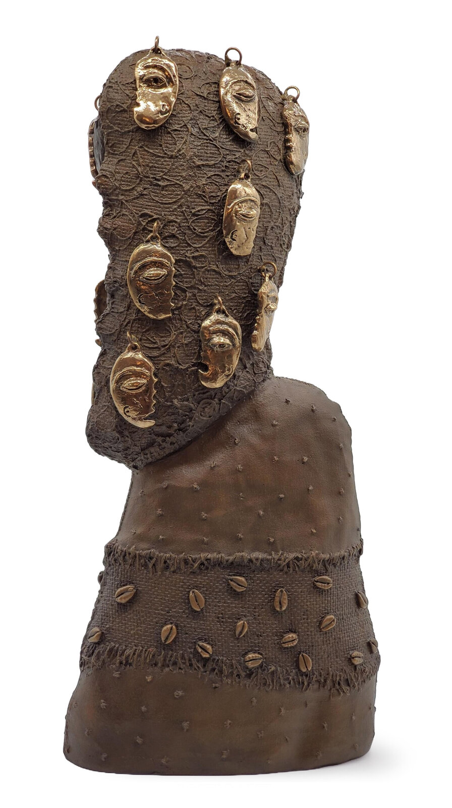 A textured bronze bust adorned with multiple gold masks and scattered cowrie shells.