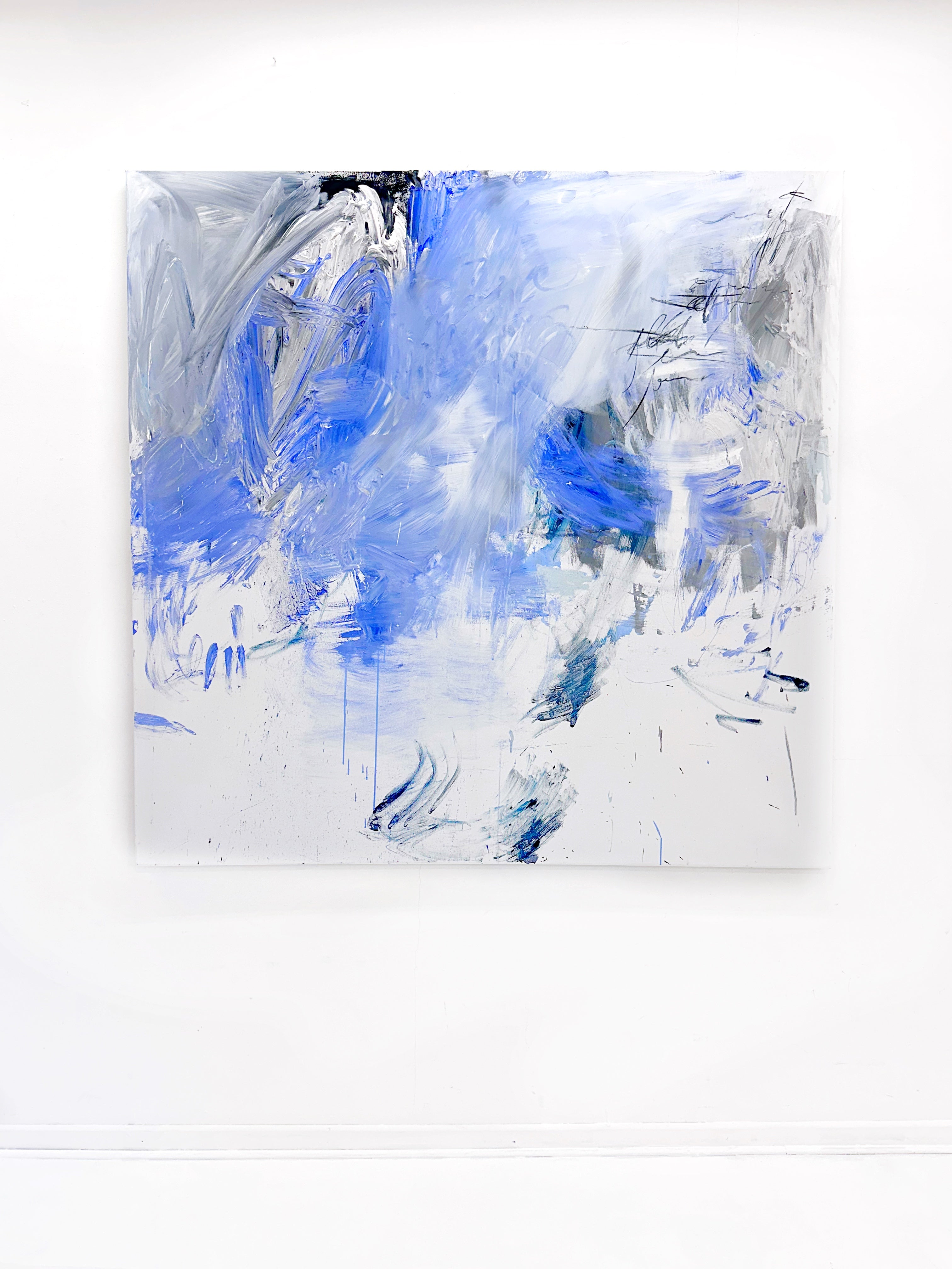 A blue and white abstract painting on a white wall.