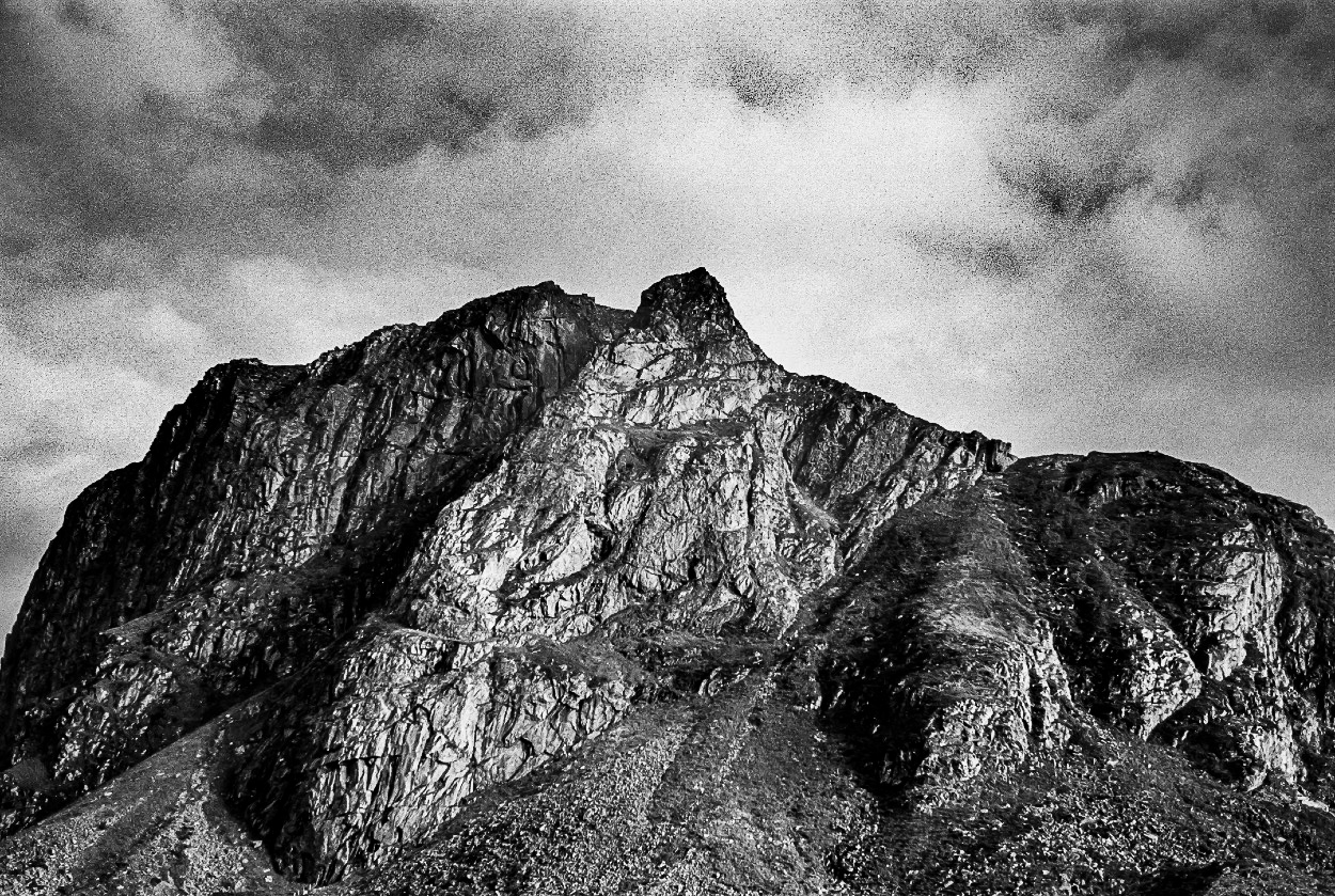 A black and white photo of a mountain with a cloudy sky.