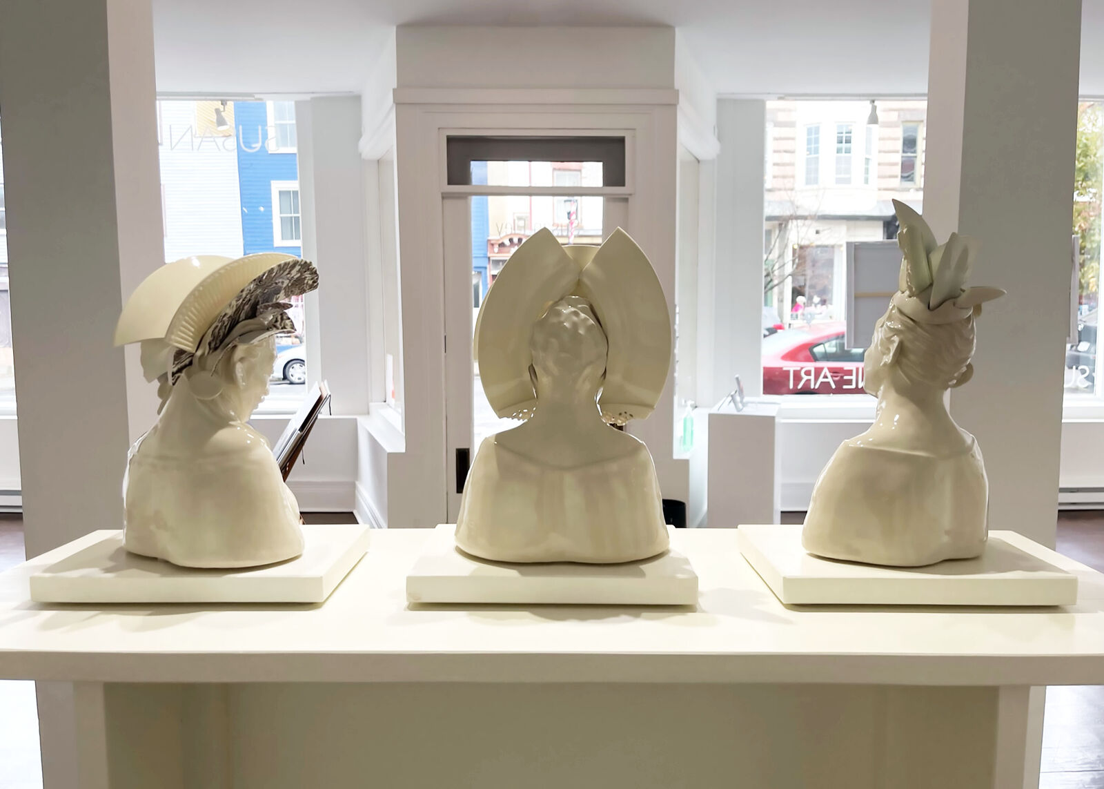 A glossy ceramic bust of a smiling figure adorned with sculpted flowers and geometric cat-ear shapes.