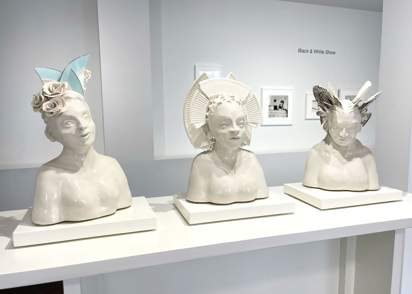 A glossy ceramic bust of a smiling figure adorned with sculpted flowers and geometric cat-ear shapes.