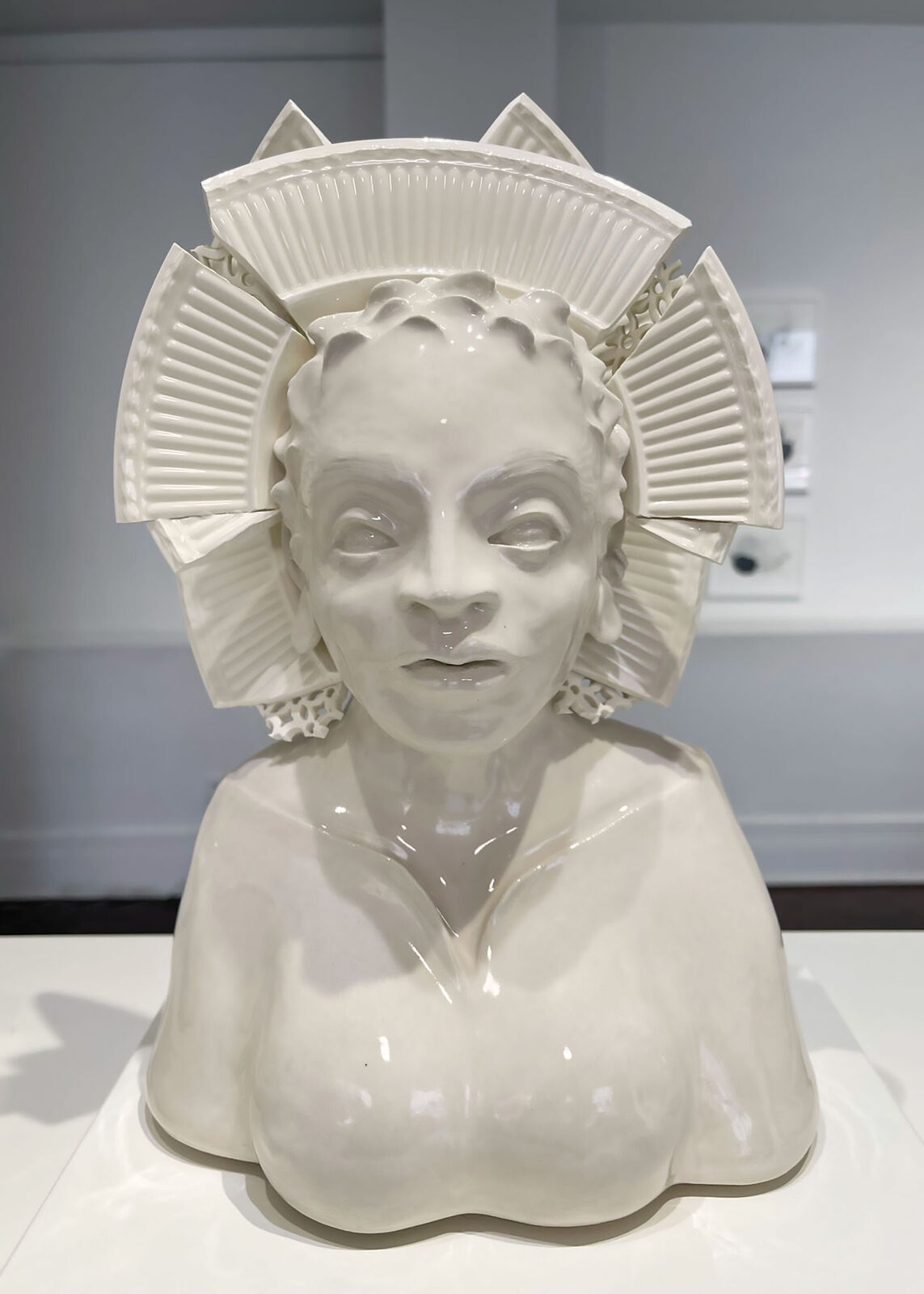 A glossy ceramic bust of a figure with an elaborate, segmented crown-like headpiece.