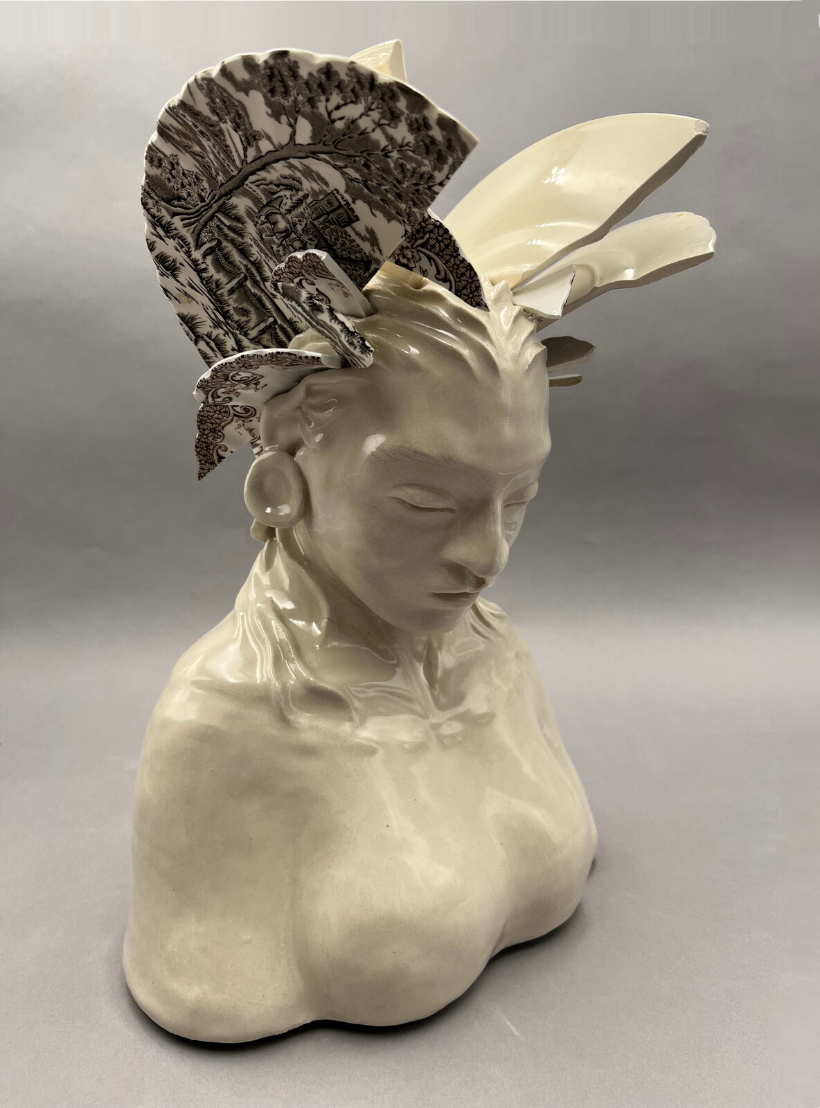 A ceramic bust adorned with broken porcelain fragments forming a headdress.