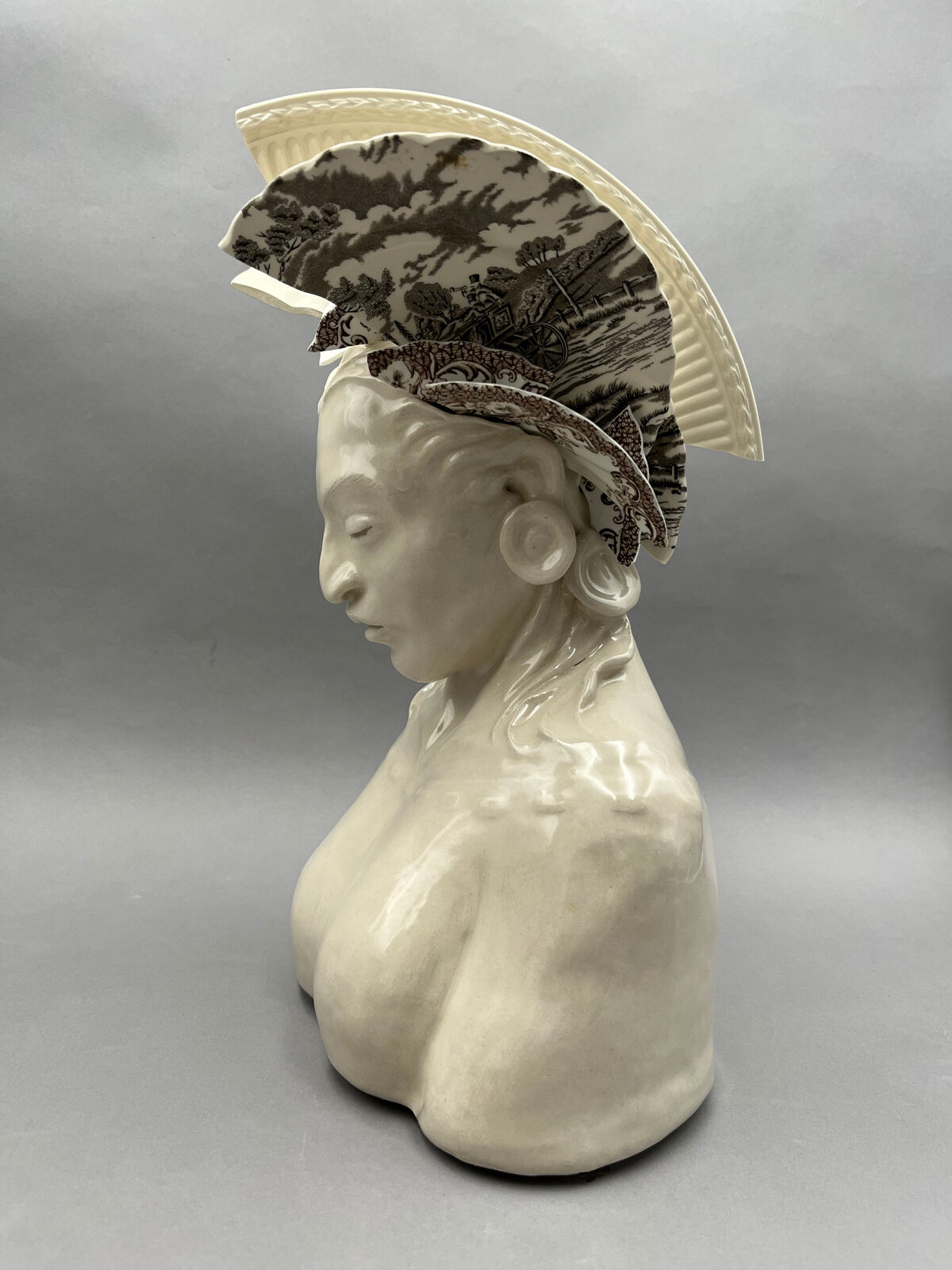 A ceramic bust adorned with broken porcelain fragments forming a headdress.