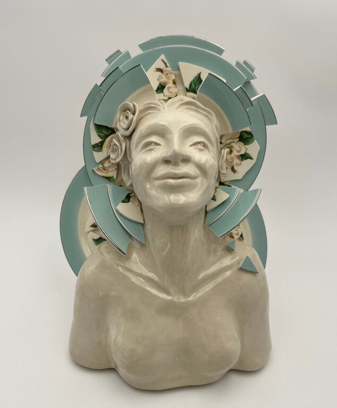 A ceramic bust with a halo of floral plates and geometric shards.