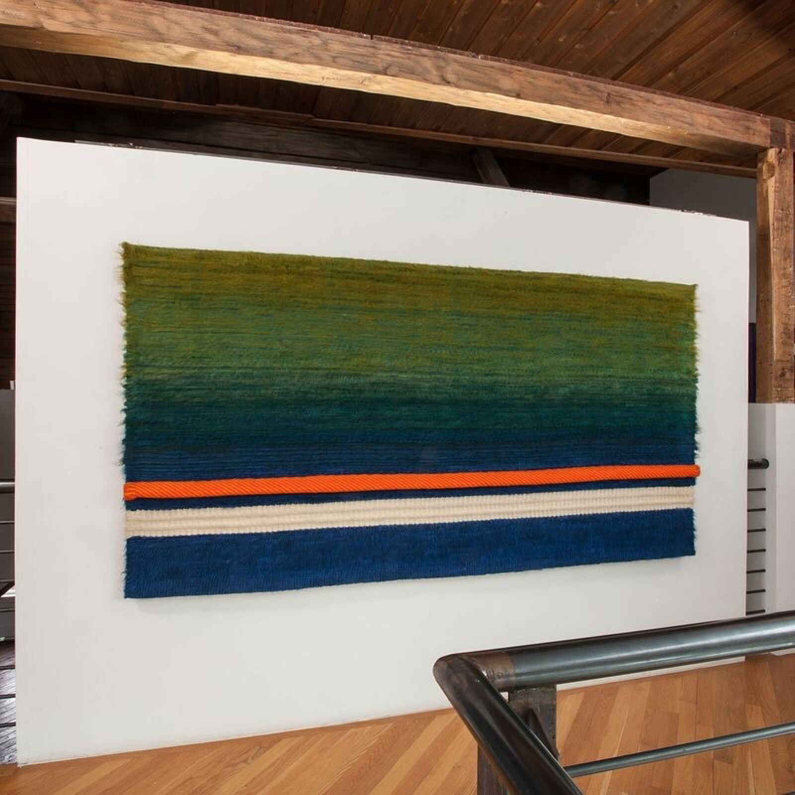 A woven textile featuring a vertical gradient from green to blue with horizontal stripes.
