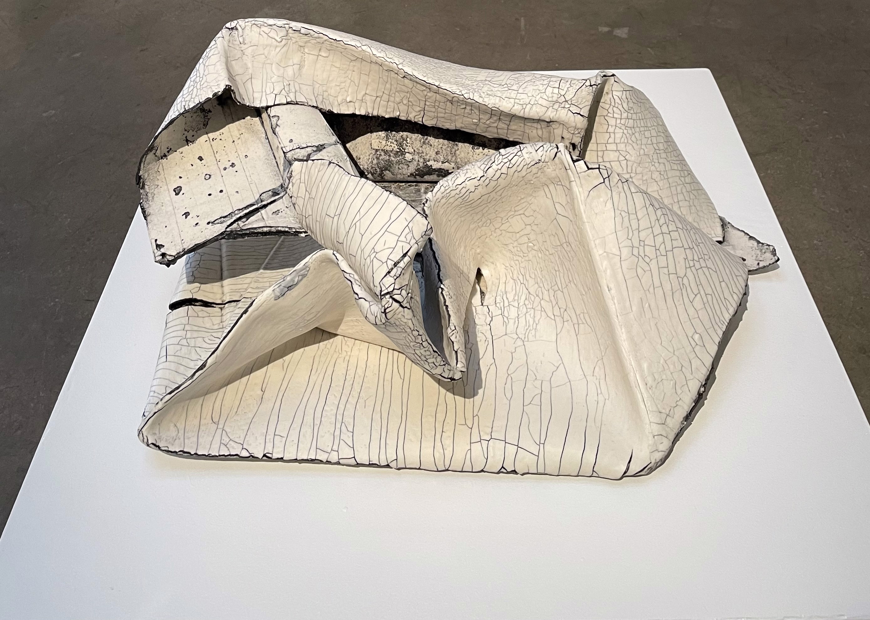 A white sculpture on a white table in a room.